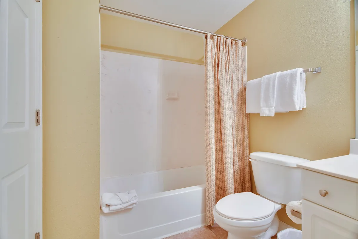 A calm, refreshing bathroom view featuring a bathtub with a shower curtain, a well-lit vanity, and tidy details that evoke both relaxation and everyday convenience.
