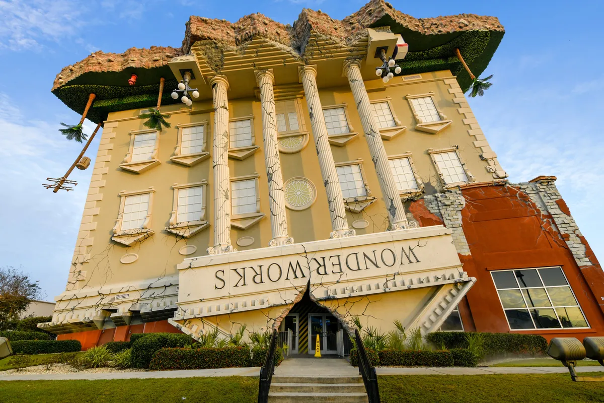 The striking upside-down WonderWorks building with its playful, exaggerated architecture and lush landscaping, inviting guests to explore unique local attractions.