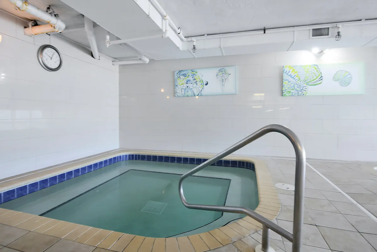A sleek, contemporary jacuzzi room with inviting warm lighting, abstract wall art, and a clock on the wall. The tranquil setting encourages relaxation and socializing after a day of exploring.