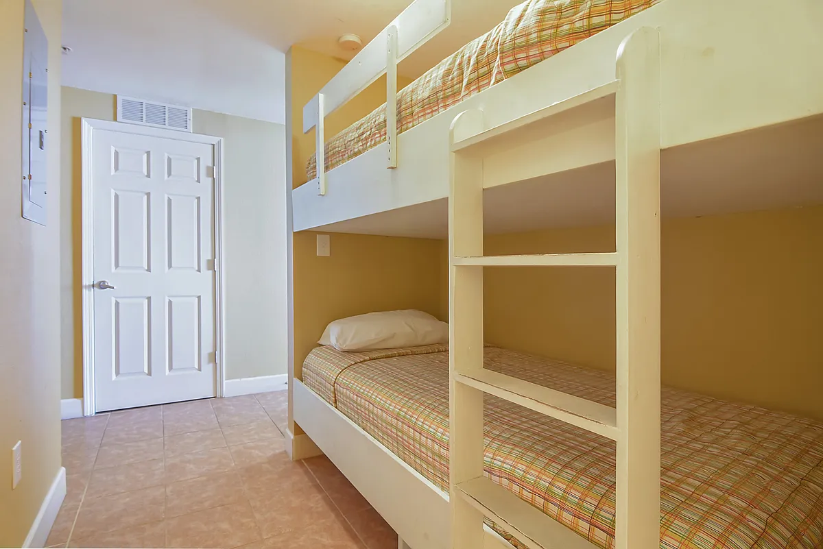 A cozy nook with twin bunk beds and a nearby doorway, creating a playful and inviting space for children. The room is styled to spark imagination and offer a sense of security for little ones.